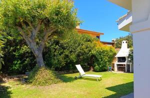 a white chair sitting in a yard next to a tree at Sa Domixedda in Villasimius