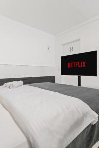 a white bed with a sign that reads netflix at Cozy Cologne Premium Apartment with free parking! NEW! in Cologne