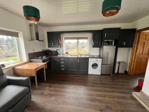 a kitchen with black cabinets and a white appliance at One Bedroom House near Ballinamore in Ballinamore