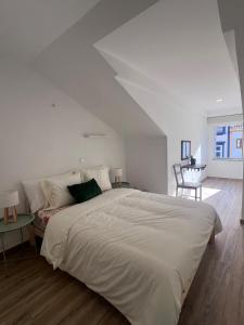 ein weißes Schlafzimmer mit einem großen Bett und einem Tisch in der Unterkunft Casa da Joana T2 no Centro Histórico de Angra in Angra do Heroísmo