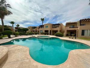 a swimming pool in a resort with palm trees and buildings at Casa Cupulas in Puerto Peñasco