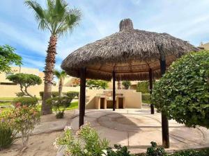Una gran sombrilla de paja con una palmera en Casa Cupulas, en Puerto Peñasco