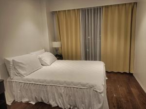 a white bed in a room with a window at Tambuli Beach Ocean view condo in Lapu Lapu City
