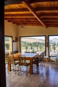 a dining room with a table and chairs and large windows at Refugio del Pescador in Esquel