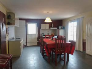 a kitchen and dining room with a red table and chairs at Casa Victoria in Catriel
