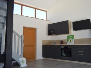 a kitchen with black cabinets and a counter top at Maison rénovée en Berry : terrasse, jardin privé, proche Châteauroux et nature - FR-1-591-164 in Saint-Maur