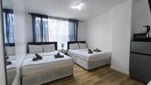 4 pers studio style room Near South Wimledon station R3 في لندن: غرفة نوم بها سريرين ونافذة