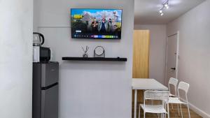 4 pers studio style room Near South Wimledon station R3 في لندن: مطبخ مع طاولة وتلفزيون على جدار