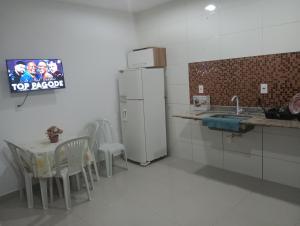 eine Küche mit einem Kühlschrank sowie einem Tisch und Stühlen in der Unterkunft Casa para vc curtir 2 in Cabo Frio + 12 Fotos