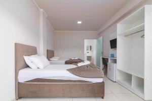 een slaapkamer met een groot bed met witte lakens en kussens bij Pousada Amanhecer do Sul in Penha