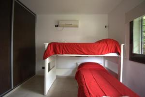 a bedroom with a bunk bed with a red blanket at LA CASITA in Roldán +47 photos