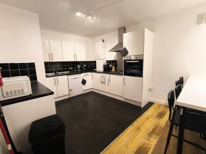 4 pers studio style room Near South Wimledon station R3 في لندن: مطبخ بدولاب بيضاء وأرضية سوداء