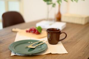 a table with a green plate and a cup of coffee at Verdant 601 in Ōdōri