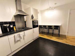 a kitchen with white cabinets and a stove top oven at 4 person room 3min from South Wimbeldon tube station Room2 in London +31 photos