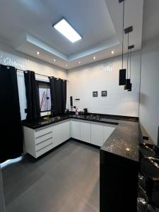 una grande cucina con mobili bianchi e ripiani neri di Casa Planalto a Piraju