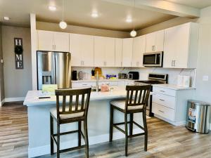 a kitchen with white cabinets and two bar stools at SINGLE HOUSE 1- Beautiful- Peaceful-4Beds 3baths- Sleeps 12 in Anchorage