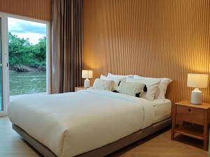 Rivendale في Ban Gaeng Cho: سرير أبيض كبير في غرفة بها نافذة