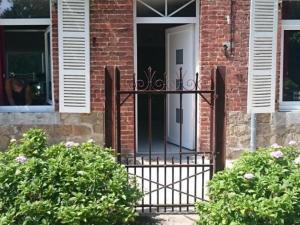 a white door on a brick house with bushes at Charmante maison avec jardin, 3 chambres, proche Val Joly - Idéal familles et randonneurs - FR-1-510-157 in Liessies +3 photos