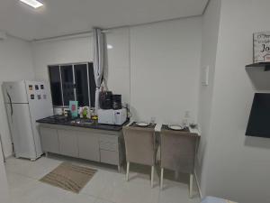 a kitchen with a refrigerator and a table and chairs at Studio CG 4, Campo Grande RJ in Estação Inhoaíba +6 photos