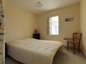 ein Schlafzimmer mit einem Bett und einem Stuhl und einem Fenster in der Unterkunft Maison calme pour 4 personnes avec jardin - FR-1-476-111 in Grues