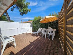 un patio avec une table, des chaises et un parasol dans l'établissement Charmante Maison Vendéenne à 350m de la Plage avec Cour Ens. et Parking - FR-1-476-180, à La Faute-sur-Mer