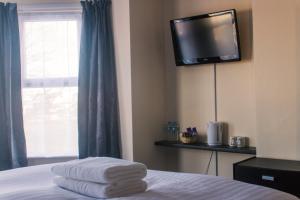 a room with a bed with a television on the wall at Wellesley Park Hotel in Great Yarmouth