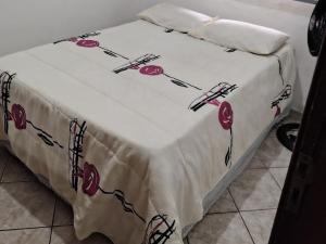 a bed with a white blanket with red flowers on it at Casinha central Manhuaçu in Manhuaçu