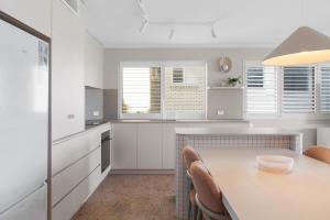 a kitchen with white cabinets and a table and chairs at Caprina in Caloundra in Caloundra +29 photos