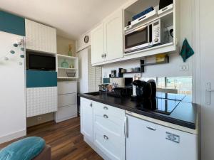 a kitchen with white cabinets and a black counter top at Studio fonctionnel 4 pers. avec accès direct plage - FR-1-323-573 in Saint-Jean-de-Monts