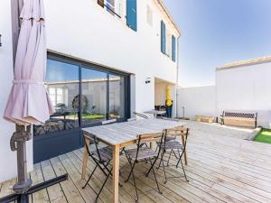 a patio with a wooden table and chairs on a deck at Maison moderne au Bois-Plage-en-Ré avec jardin - FR-1-835-3 in Le Bois-Plage-en-Ré