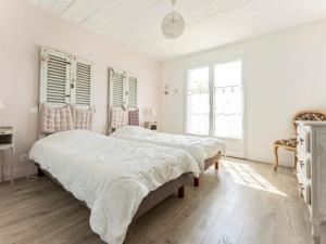 two beds in a bedroom with white walls and wood floors at Maison familiale avec piscine pour 9 personnes - FR-1-835-4 in Le Bois-Plage-en-Ré +24 photos