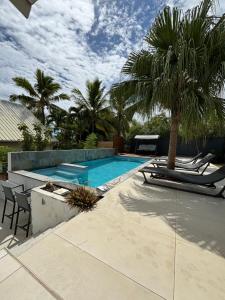 a swimming pool with two chairs and a palm tree at La Villa Manee in La Saline les Bains