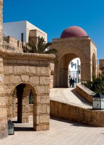 a stone archway with a building with a dome at Diar Lemdina Hotel in Hammamet
