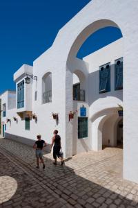 two men walking in front of a white building at Diar Lemdina Hotel in Hammamet