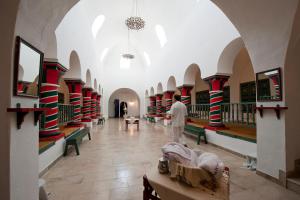 a man walking through a large room with tables and benches at Diar Lemdina Hotel in Hammamet