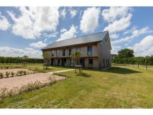 Un gran edificio en un campo con un patio de césped. en Holiday Home in Vrouwenpolder near Beach, en Vrouwenpolder