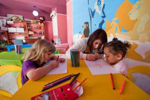 a woman and two girls drawing at a table at Diar Lemdina Hotel in Hammamet