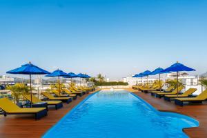 a pool with yellow chairs and blue umbrellas at Days Inn by Wyndham Patong Beach in Patong Beach