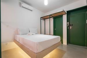 a bedroom with a large white bed with green doors at Apartamentos inCircle in Sao Paulo