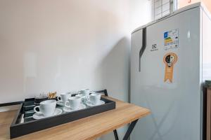 a tray of coffee cups on a table next to a refrigerator at Apartamentos inCircle in Sao Paulo