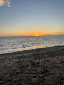 a beach with the sun setting over the ocean at La Villa Manee in La Saline les Bains