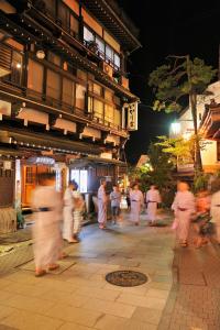 a group of people walking down a street at night at Ikariya Ryokan in Yamanouchi