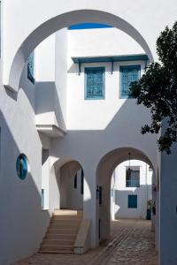 an archway leading up to a white building with stairs at Diar Lemdina Hotel in Hammamet
