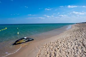a boat sitting on a sandy beach next to the ocean at Diar Lemdina Hotel in Hammamet