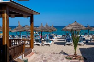a beach with chairs and umbrellas and the ocean at Diar Lemdina Hotel in Hammamet