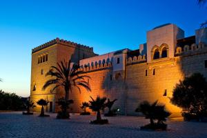 a large building with palm trees in front of it at Diar Lemdina Hotel in Hammamet