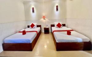 2 letti con cuscini rossi in una camera di Nice Guesthouse a Phnom Penh