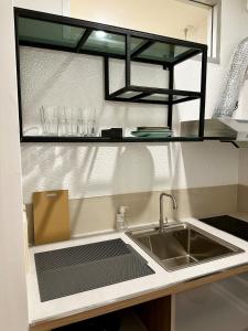 a kitchen counter with a sink and a shelf with glasses at Studio Botanica I 2 mins to SRT in Bangkok