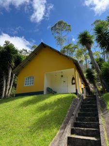 a yellow house with palm trees in front of it at Belo Canto Chalés in Santa Teresa