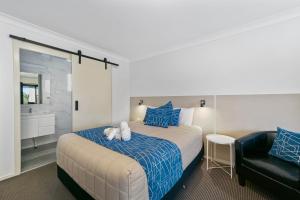 a bedroom with a bed and a black chair at Kandos Fairways Motel in Kandos